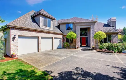 Large modern house with three garage spaces and concrete driveway.