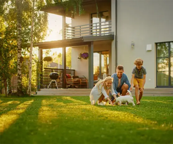 Smiling Father, Mother and Son Pet and Play with Smooth Fox Terrier Retriever Dog. Sun Shines on Idyllic Happy Family with Loyal Pedigree Dog have Fun at the Idyllic Suburban House Backyard.